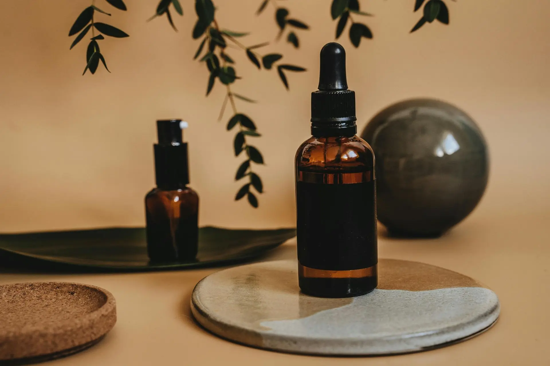Soothing essential oil display for relaxation and wellness Amber essential oil bottle with dropper on ceramic tray and botanical backdrop.